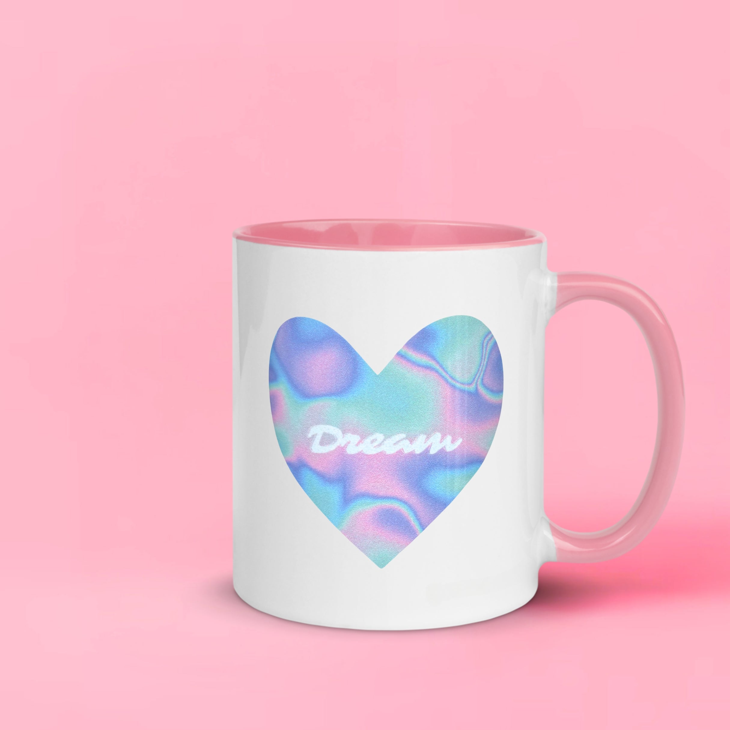 A pink and white two-toned mug, with an image of a blue, purple and pink multi-coloured heart, and text that says 'Dream'. 